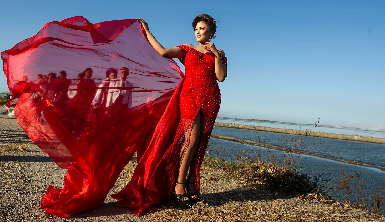 Model dengan balutan busana tradisional berlenggak-lenggok saat fashion show di tanggul Lapindo Porong, Sidoarjo, Jawa Timur, Selasa (13/8/2019). Sebanyak 15 model menunjukkan mode busana yang didominasi warna merah dan putihdalam acara tersebut. (Photo by JUNI KRISWANTO / AFP)