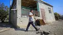 Seorang pria berjalan melewati sebuah rumah yang rusak akibat penembakan selama pertempuran Azerbaijan dan Armenia dalam memperebutkan wilayah Nagorno-Karabakh di Agdam, Azerbaijan, Senin (19/10/2020). Pertempuran di Nagorno-Karabakh berkecamuk selama lebih dari tiga minggu. (AP Photo/Aziz Karimov)