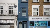 Seorang pejalan kaki melewati bagian depan bangunan yang dijuluki "Rumah Tersempit di London" (cat biru) di London barat pada 5 Februari 2021. Rumah unik yang terdiri dari lima tingkat tersebut dibanderol dengan harga mencapai £ 990.000 atau senilai dengan Rp 19,4 miliar. (Tolga Akmen/AFP)