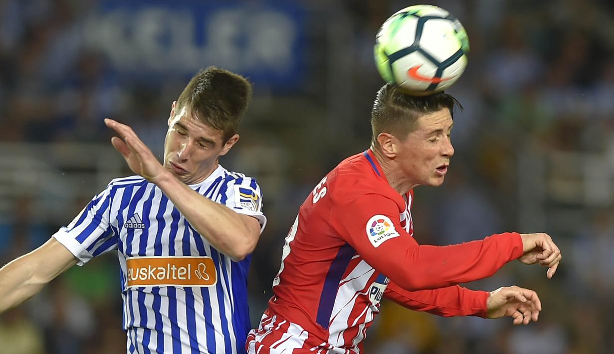 Striker Atletico Madrid, Fernando Torres, duel udara dengan bek Real Sociedad, Aritz Elustondo, pada laga La Liga di Stadion Municipal de Anoeta, Kamis (19/4/2018). Real Sociedad menang 3-0 atas Atletico Madrid. (AFP/Ander Gillenea)