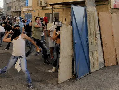 Warga Palestina melempar batu ke arah polisi Israel dalam bentrokan di Shuafat, sebuah daerah pinggiran Arab, Yerusalem, Senin (5/10/2015). Seorang remaja Palestina tewas pada Senin dalam bentrokan di Tepi Barat. (REUTERS/Ammar Awad)