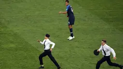 Pemain timnas Prancis, Raphael Varane melihat dua orang penyusup masuk ke lapangan pada laga final Piala Dunia 2018 melawan Kroasia di Luzhniki Stadium, Minggu (15/7). Empat orang berseragam polisi menyusup masuk ke dalam lapangan (AP/Thanassis Stavrakis)