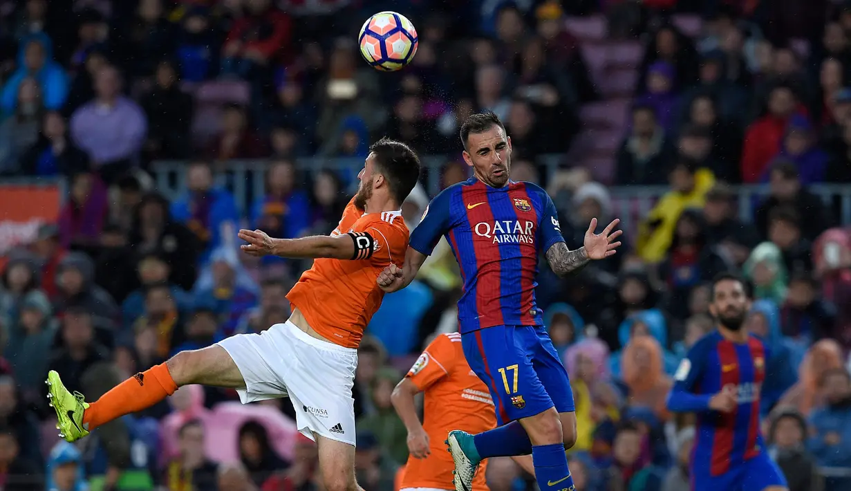 Pemain depan Barcelona Paco Alcacer berebut bola diudara dengan pemain belakang Osasuna Oier saat pertandingan liga Spanyol antara Barcelona vs Osasuna di stadion Camp Nou, Barcelona (26/4). (AFP/Lluis Gene)