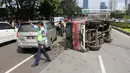 Petugas mengatur lalu lintas akibat mobil boks terguling di Jalan Casablanca, Jakarta, Rabu (27/6). Mobil bernomor polisi B 9515 FCC yang dikemudikan oleh Sumarno menabrak pembatas jalan. (Liputan6.com/Arya Manggala)