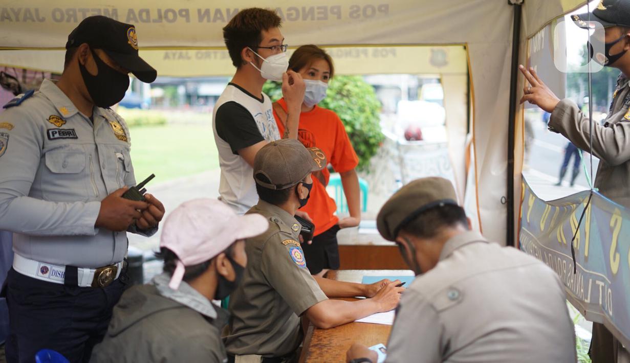 Petugas gabungan mendata warga yang terjaring Operasi Yustisi Protokol Covid-19 di kawasan Tugu Tani, Jakarta, Senin (14/9/2020). Operasi tersebut digelar sebagai langkah untuk menekan penyebaran Covid-19 di masa PSBB Jakarta. (Liputa6.com/Immanuel Antonius)