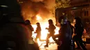 Petugas kepolisian melewati api yang dinyalakan oleh demonstran saat berunjuk rasa di Hamburg, Kamis (6/7). Polisi antihuru-hara Jerman bentrok dengan para pengunjuk rasa menjelang pertemuan puncak KTT G20 yang digelar pada 7-8 Juli. (AP/Markus Schreiber)