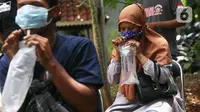 Warga meniupkan kantong saat menjalani tes deteksi COVID-19 dengan metode GeNose C19 usai terjaring razia penggunaan masker di Kelurahan Sudimara Barat, Kota Tangerang, Kamis (27/5/2021). Tes tersebut untuk menekan penyebaran corona di wilayah tersebut. (Liputan6.com/Angga Yuniar)