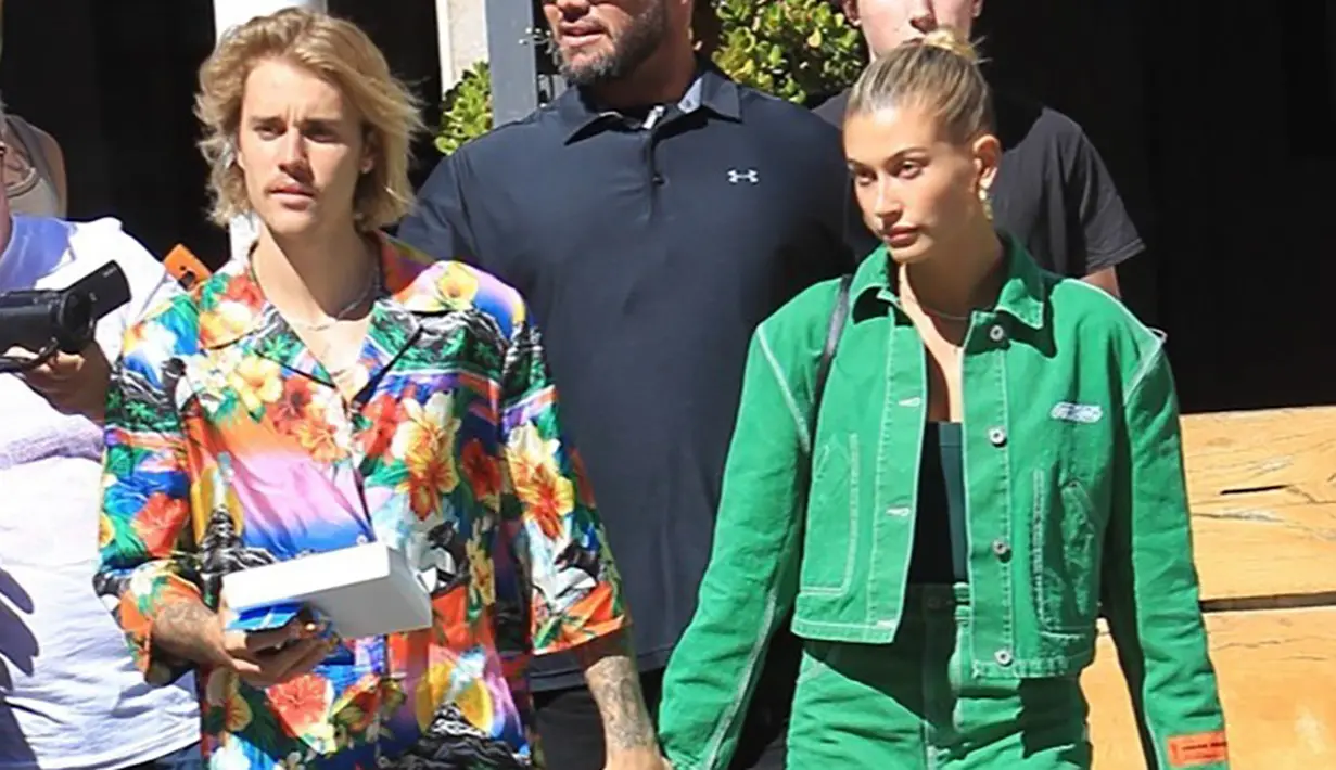 Hailey Baldwin dan Justin Bieber terlihat santai. Justin memakai kemeja hawa dengan jean pendek. Semenara Hailey menggunakan rok denim hijau yang matching dengan atasannya. (SPLASHNEWS COM/HollywoodLife)