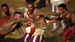 Pemain berebut bola saat pertandingan Calcio Storico Fiorentino di Piazza Santa Croce di Florence, Italia (24/6). Permainan ini selalu diselenggarakan di kota Florence, oleh karenanya sering disebut juga Calcio Fiorentino. (AFP Photo/Filippo Monteforte)