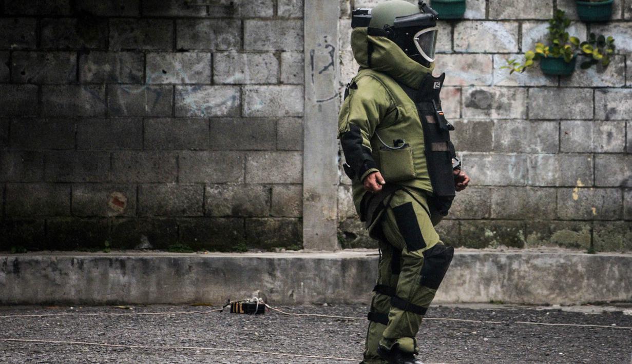 Benda mencurigakan tersebut ditemukan pertama kali oleh warga sekitar pukul 08.30 WIB. Tampak dalam foto, seorang petugas polisi dari unit penjinak bom memeriksa sebuah benda mencurigakan berbentuk kotak yang dibungkus lakban hitam dengan kabel di depan Gereja Kristen Protestan Simalungun (GKPS) di Bandung, Jawa Barat pada Jumat 19 Desember 2025. (Timur Matahari/AFP)