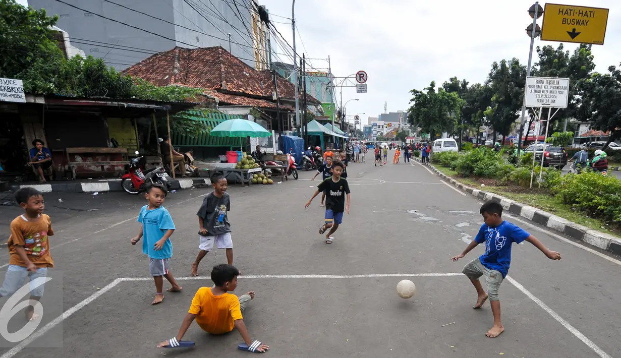 Sejumlah anak bermain sepak bola di Jalan Tambak, Manggarai, Jakarta, Jumat (22/7). Minimnya lahan bermain, sejumlah anak manfaatkan jalanan untuk bermain. (Liputan6.com/Yoppy Renato)