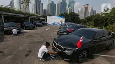 Petugas membersihkan mobil BMW i7 dan i5 di komplek GBK, Senayan, Jakarta, Jumat (3/5/2024). (Liputan6.com/Angga Yuniar)