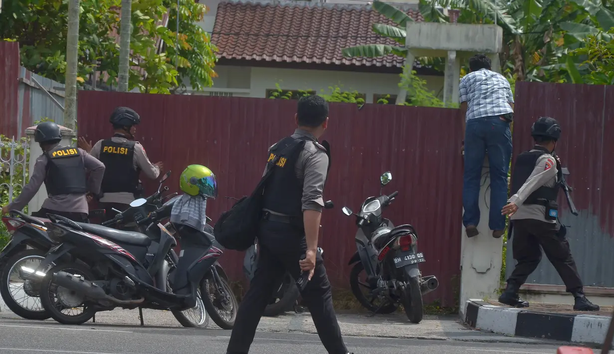 Petugas kepolisian memburu pelaku penyerangan di sekitar markas polisi di Pekanbaru, Riau (16/5). Dalam serangan tersebut satu perwira tewas dan dua lainnya terluka. (AFP Photo/Dedy Sutisna)