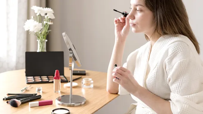 Seorang perempuan sedang bercermin sambil menggunakan make up (Foto Dok: Freepik/freepik)