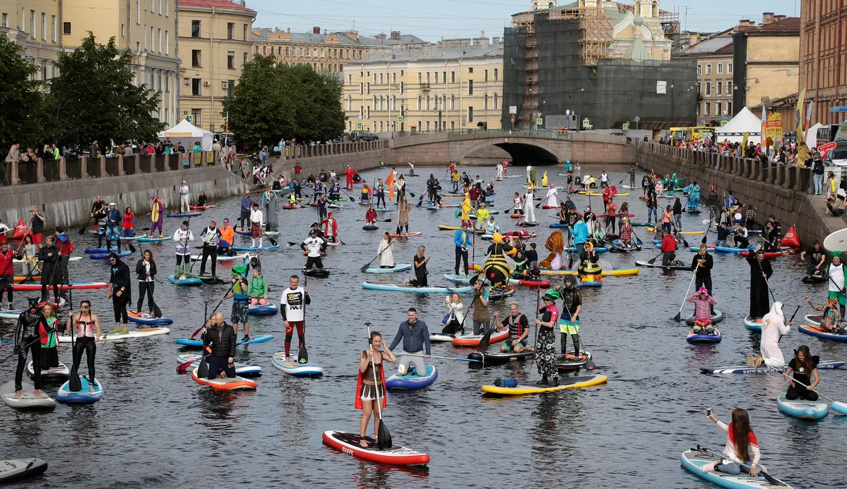 Suasana sejumlah peserta yang mengenakan kostum mendayung papan Stand Up Paddle (SUP) mereka di kanal Kryukov saat Surfing festival di St.Petersburg, Rusia (8/7). Olahraga ini menjadi sangat populer sejak tahun 2005. (AP Photo / Dmitri Lovetsky)