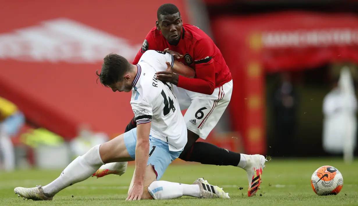 Pemain Manchester United, Paul Pogba, berebut bola dengan pemain West Ham United, Declan Rice, pada laga Premier League di Stadion Old Trafford, Rabu (22/7/2020). Kedua tim bermain imbang 1-1. (Clive Brunskill/Pool via AP)