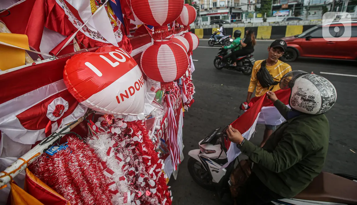 Seorang pedagang bendera merapikan umbul-umbul dan bendera yang di jual di Sepanjang Jalan Jatinegara, Jakarta, Selasa (2/8/2022). Jelang peringatan HUT Kemerdekaan RI ke-77, pedagang musiman bendera  mulai bermunculan mereka memanfaatkan trotoar untuk memajang dagangannya, mulai dari umbul-umbul, bendera, hingga ornamen khas merah putih lainnya dengan harga yang tawarkan juga bervariasi, mulai dari Rp. 5.000 ,- hingga Rp. 300.000,. (Liputan6.com/Faizal Fanani)