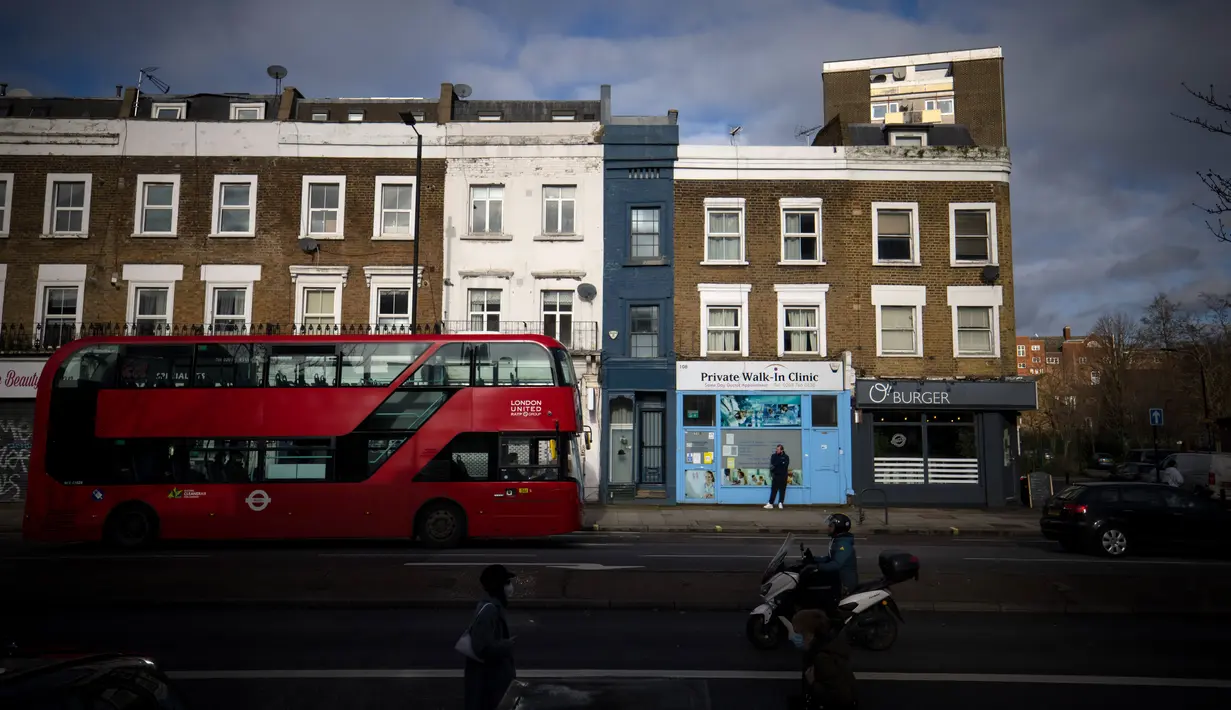 Pejalan kaki dan lalu lintas melewati bagian depan "Rumah Tersempit di London" (cat biru) di London barat pada 5 Februari 2021. Rumah tersempit ini menampung banyak ruangan, termasuk tiga kamar tidur, teras atap, kamar mandi, taman hingga dapur dan ruang tamu di lantai bawah tanah. (Tolga Akmen/AFP)