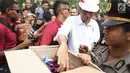 Presiden Joko Widodo atau Jokowi saat membagikan buku dan kain batik kepada warga sekitar Bandara Soetta, Tangerang, Banten, Kamis (21/6). Bagi-bagi buku tersebut merupakan rutinitas Jokowi usai blusukan. (Liputan6.com/Angga Yuniar)