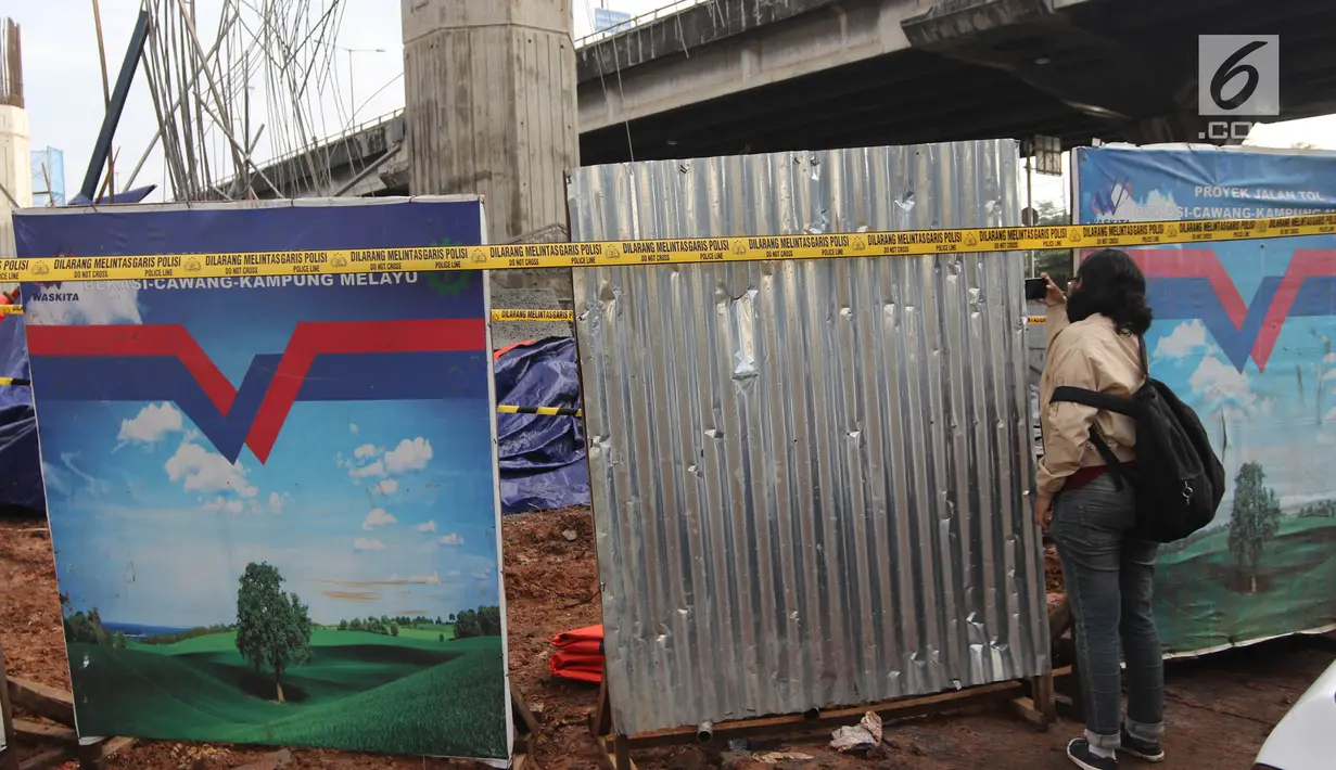 Seorang wanita mengambil gambar tiang girder Tol Bekasi-Cawang-Kampung Melayu (Becakayu) yang ambruk di Kebon Nanas, Jakarta Timur, Selasa (20/2). Peristiwa terjadi saat para pekerja melakukan pengecoran pada penyangga tiang. (Liputan6.com/Arya Manggala)