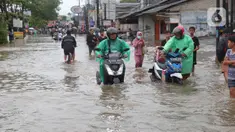 Warga berusaha melintasi genangan air ketika banjir merendam Jalan KH. Hasyim Ashari, Tangerang, Banten, Sabtu (16/7/2022). Akibat luapan kali angke ruas jalan yang menghubungkan Tangerang-Jakarta itu terputus akibat banjir. (Liputan6.com/Angga Yuniar)