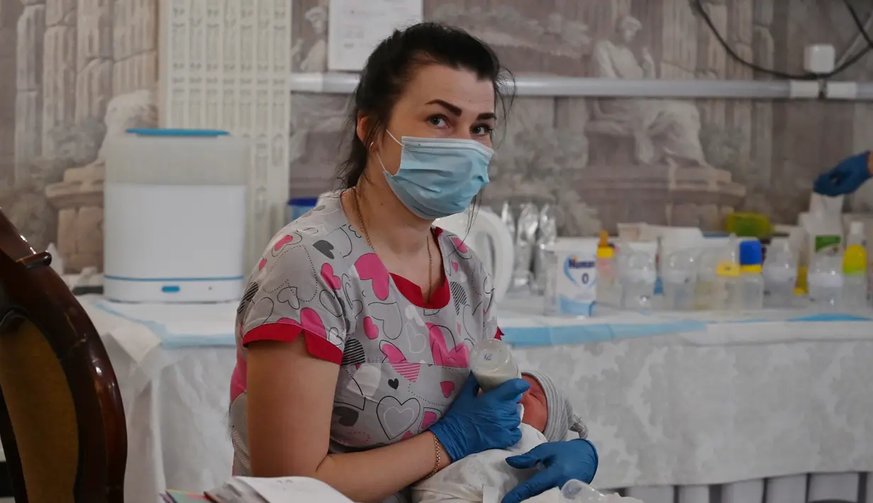 Perawat merawat bayi yang baru lahir dari skema ibu pengganti (surrogate mother) di Hotel Venice, Kiev, Ukraina, 15 Mei 2020.  Menurut Ombudsman Ukraina, jika karantina diperpanjang maka jumlah bayi yang telantar bisa mencapai ribuan. (Sergei SUPINSKY/AFP)