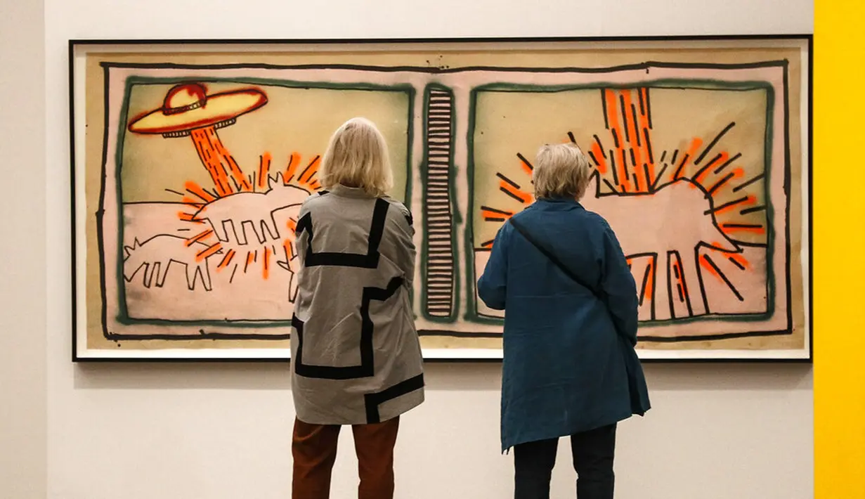 Pengunjung mengamati karya seni seniman Amerika Serikat Keith Haring saat pameran di Museum Folkwang, Essen, Jerman, Selasa(1/9/2020). Keith Haring merupakan seniman jalanan asal New York yang meninggal akibat komplikasi AIDS pada tahun 1990. (AP Photo/Martin Meissner)