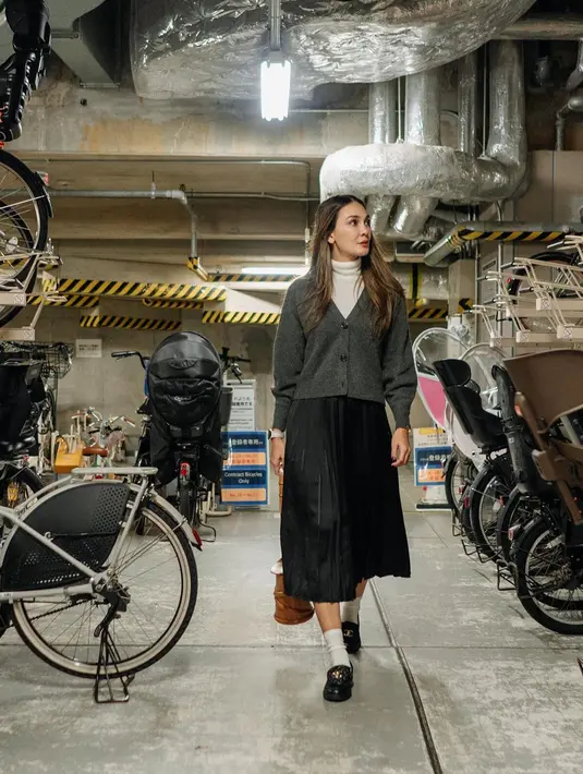 Gaya yang lebih chic ala Luna Maya. Ia mengenakan turtleneck putih yang ditumpuk dengan oversized cardigan abu-abu dan dipadu dengan midi pleated skirt berwarna hitam, dipermanis dengan loafers hitam. Foto: Instagram.