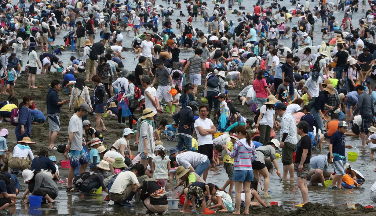 Sejumlah pengunjung menggali pasir untuk berburu kerang di pantai kawasan Yokohama, dekat Tokyo, Senin (30/4). Puluhan ribu orang berdesakan di pantai selama Golden Week atau periode liburan di Jepang pada akhir April hingga awal Mei. (AP/Koji Sasahara)