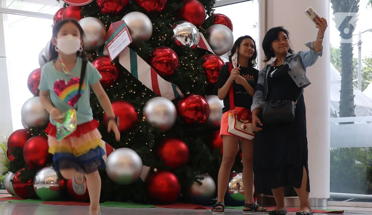 Pengunjung berfoto dengan latar belakang pernak pernik Natal di Living World, Tangerang Selatan, Senin (13/12/2021). Jelang perayan Natal sejumlah pusat perbelanjaan dihiasi ornamen Natal yang dijual. (Liputan6.com/Anga Yuniar)