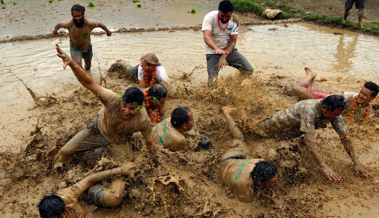 Sejumlah warga Nepal bermain di lumpur pada Asar Pandra, atau hari menanam padi di Lalitpur, 29 Juni 2018. Asar Pandra diadakan sebagai tanda dimulainya kembali aktivitas tanam padi di sawah saat musim hujan tiba. (AP Photo/Niranjan Shrestha)