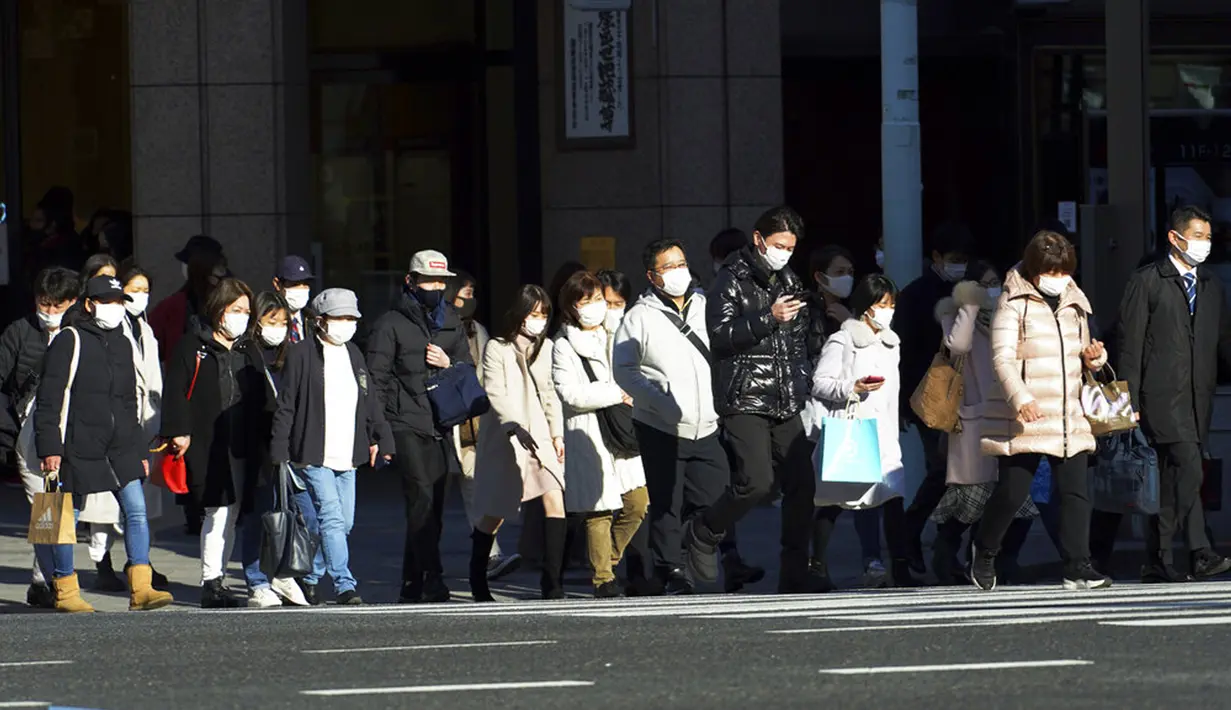 Orang-orang yang mengenakan masker pelindung untuk membantu mengekang penyebaran COVID-19 berjalan kaki di Tokyo, Jepang, Kamis, (4/2/2021). Tokyo mengonfirmasi lebih dari 730 kasus baru COVID-19 pada 4 Februari 2021. (AP Photo/Eugene Hoshiko)
