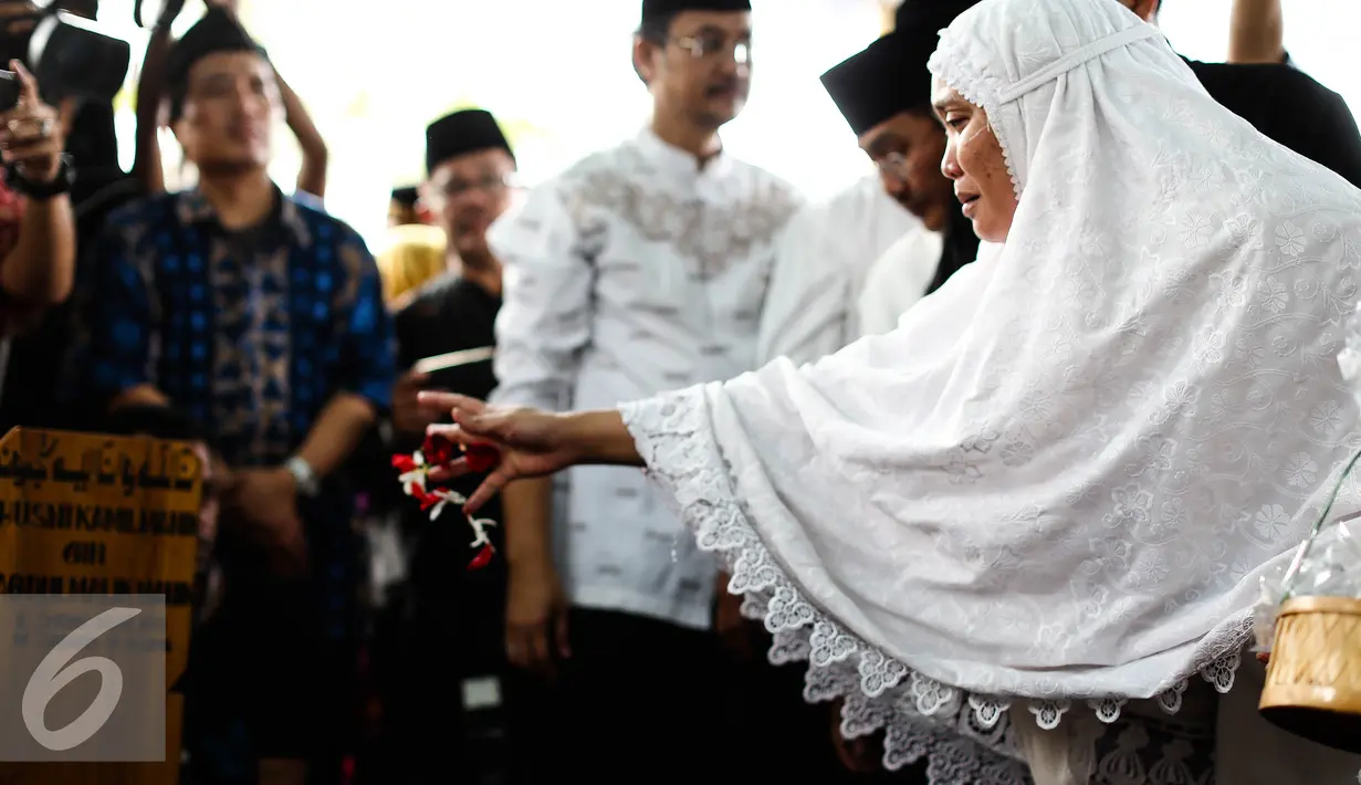 Istri Alm Husni Kamil Malik menebar bunga pemakaman Alm Husni Kamil Malik  di TPU Jeruk Purut, Jakarta, Rabu (8/7). Husni Kamil Manik meninggal semalam saat menjalani perawatan di RS Pusat Pertamina. (Liputan6.com/Faizal Fanani)