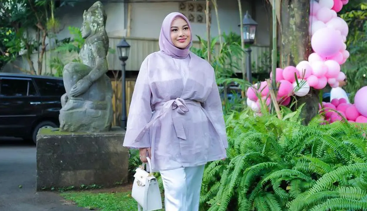 <p>Dalam unggahan foto, ia tampil anggun mengenakan atasan organza dan hijab lilac dipadukan dengan celana panjang warna putih. @aurelie.hermansyah.</p>