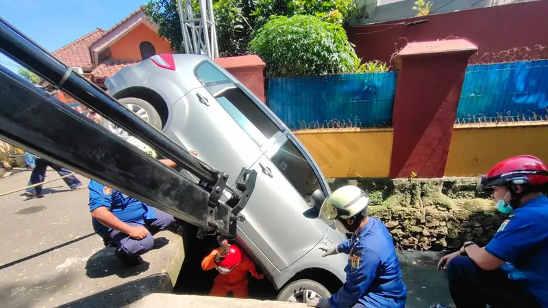 Petugas Damkar mengevakuasi mobil yang terpersok ke selokan di Jalan Pembaharuan, Kelapa Dua Wetan, Ciracas, Jakarta Timur