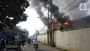 Asap hitam membumbung dari atas Gudang JNE Express yang terbakar di Jalan Pekapuran Raya, Depok, pada Senin (12/9/2022). Setidaknya ada 12 unit mobil pemadam yang dikerahkan untuk memadamkan api. (Liputan6.com/Herman Zakharia)