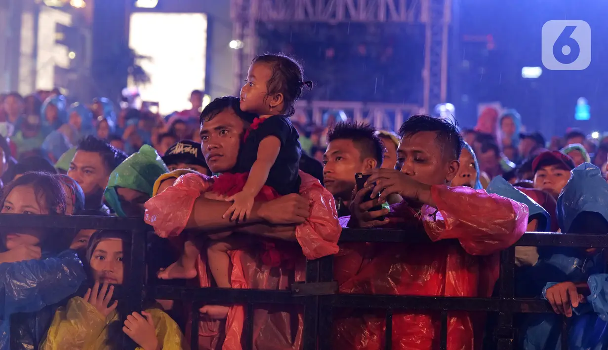 Sejumlah warga menyaksikan Rhoma Irama selama konser Happy New Year 2020 di Bundaran HI, Jakarta, Selasa (31/12/2019). Raja Dangdut Rhoma Irama dan Soneta Group menjadi band utama yang mengiringi musik legendarisnya di konser tersebut. (Liputan6.com/Herman Zakharia)