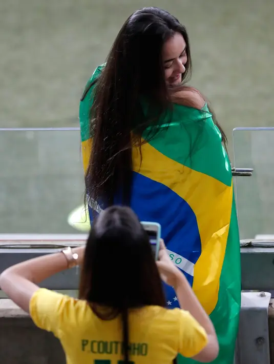 Fans wanita berpose dengan bendera Brasil sebelum pertandingan antara Brasil melawan Argentina pada semifinal Copa America 2019 di Stadion Mineirao, Brasil (2/7/2019). Di pertandingan ini Brasil menang 2-0 atas Argentina berkat gol striker Gabriel Jesus dan Roberto Firmino. (AP Photo/Nelson Antoine)