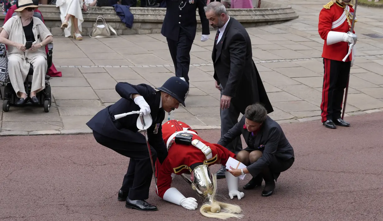 Menantang panas untuk kedua kalinya sejak akhir pekan, anggota Household Cavalry dan Yeoman Warders berbaris di jalan-jalan Windsor saat Raja memimpin prosesi menuju Kapel St George. (AP Photo/Kirsty Wigglesworth, Pool)