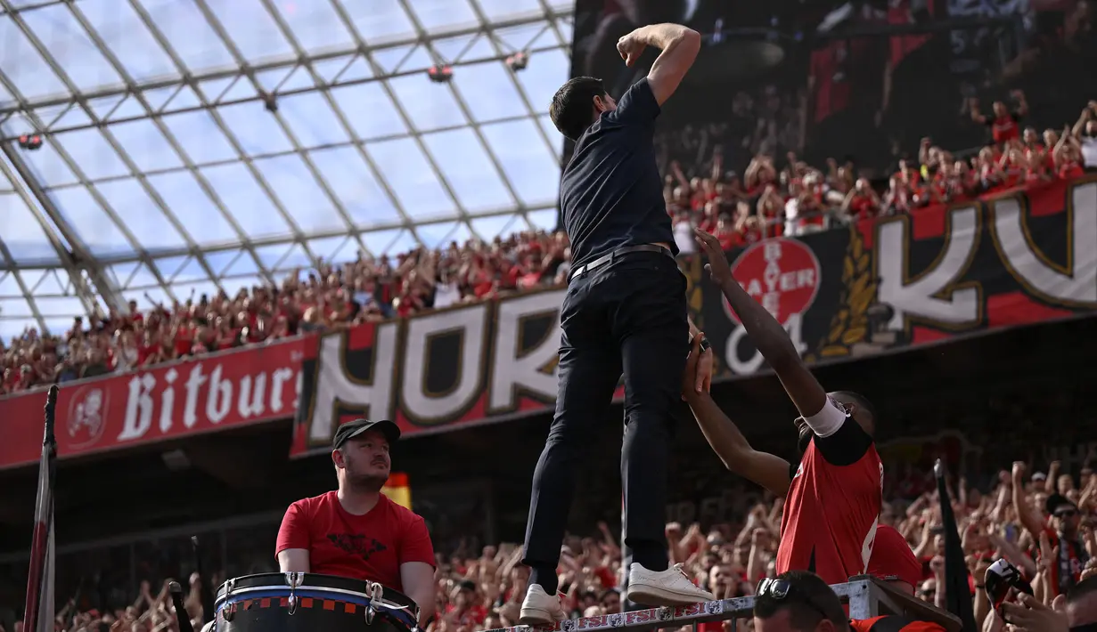 Pelatih Bayer Leverkusen, Xabi Alonso memimpin chant di depan para fans setelah laga lanjutan Liga Jerman 2024/2025 melawan Borussia Dortmund di BayArena, Leverkusen, Jerman, Minggu (11/05/2025) waktu setempat. (AFP/Ina Fassbender)