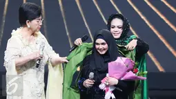 Hetty Koes Endang memakaikan kain hadiah ulang tahun untuk Siti Nurhaliza dalam acara Golden Memories International di Indosiar, Jakarta, Kamis (12/1). (Liputan6.com/Yoppy Renato)