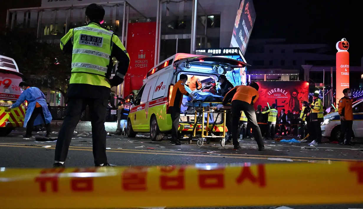 <p>Staf medis merawat seseorang di atas tandu di distrik kehidupan malam populer Itaewon di Seoul, Korea Selatan, Minggu (30/10/2022) . Orang-orang dalam kerumunan di gang sempit itu dikabarkan sempat saling dorong. Selain berdesakan, banyak pula yang terinjak-injak hingga jumlah korban tewas dalam pesta Halloween di Itaewon melonjak. (Photo by JUNG YEON-JE / AFP)</p>