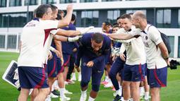 Staf kepelatihan menyambut kedatangan pemain PSG, Kylian Mbappe (tengah), dengan sukacita sebelum menjalani sesi latihan bersama pemain PSG lainnya di Poissy, Senin (14/8/2023). (Twitter/@PSG_English)
