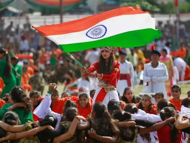 Seorang gadis mengibarkan bendera India saat para siswa melakukan tarian selama perayaan Hari Kemerdekaan India, di Jammu, India, (15/8). India merdeka dari kolonialis Inggris pada tahun 1947. (AP Photo / Channi Anand)