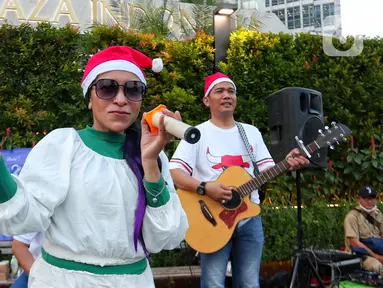 Musisi mengelar pertunjukan musik bernuansa Natal di jalur Pedestrian Bundaran HI, Jakarta Pusat, Selasa (20/12/2022). Pergelaran musik bernuansa Natal tersebut sebagai bentuk pertunjukan untuk menghibur warga yang melintas di Kawasan itu. (Liputan6.com/Angga Yuniar)
