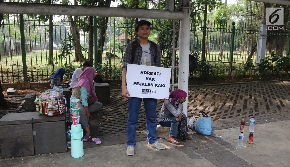 Koalisi Pejalan Kaki menunjukkan poster yang berisi imbauan saat melakukan aksi Tamasya Trotoar Kita di Jalan Medan Merdeka Selatan, Jakarta, Minggu (24/6). (Liputan6.com/Arya Manggala)