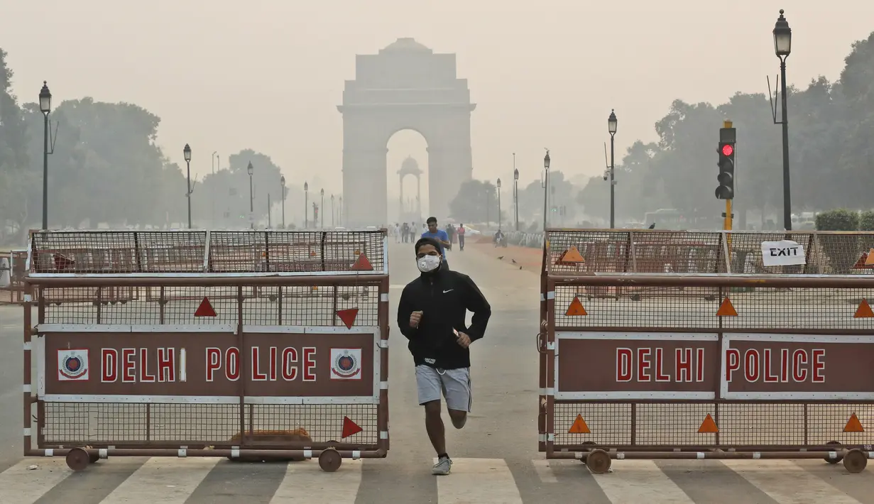 Seorang pria India berlari mengenakan masker pada pagi hari di tengah kabut tipis di New Delhi, India (28/10/2019). Menurut pemerintah New Delhi kualitas udara buruk setelah festival Hindu Diwali tahun ini masih lebih baik daripada tiga tahun terakhir. (AP Photo/Manish Swarup)