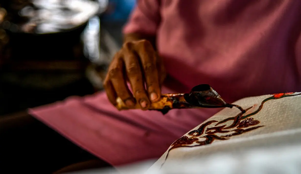 Seorang pekerja membuat desain batik di sebuah bengkel di Banda Aceh, Aceh, Rabu (13/10/2021). Pemilihan warna membuat kain batik Aceh terlihat cerah dan juga glamor. (Chaideer MAHYUDDIN/AFP)
