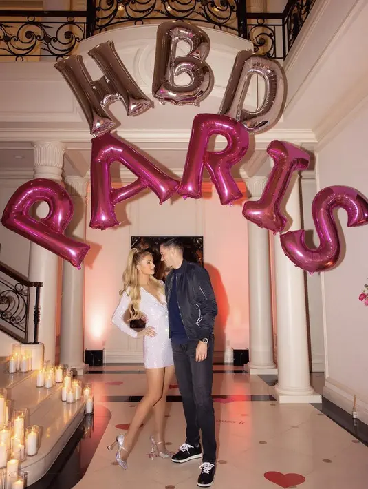 Saat ulang tahun, Paris tampil dengan mini dress long sleeve sqeuin putih dipadukan heels. Sang saumi nampak mengenakan bomber jaket. (@parishilton)