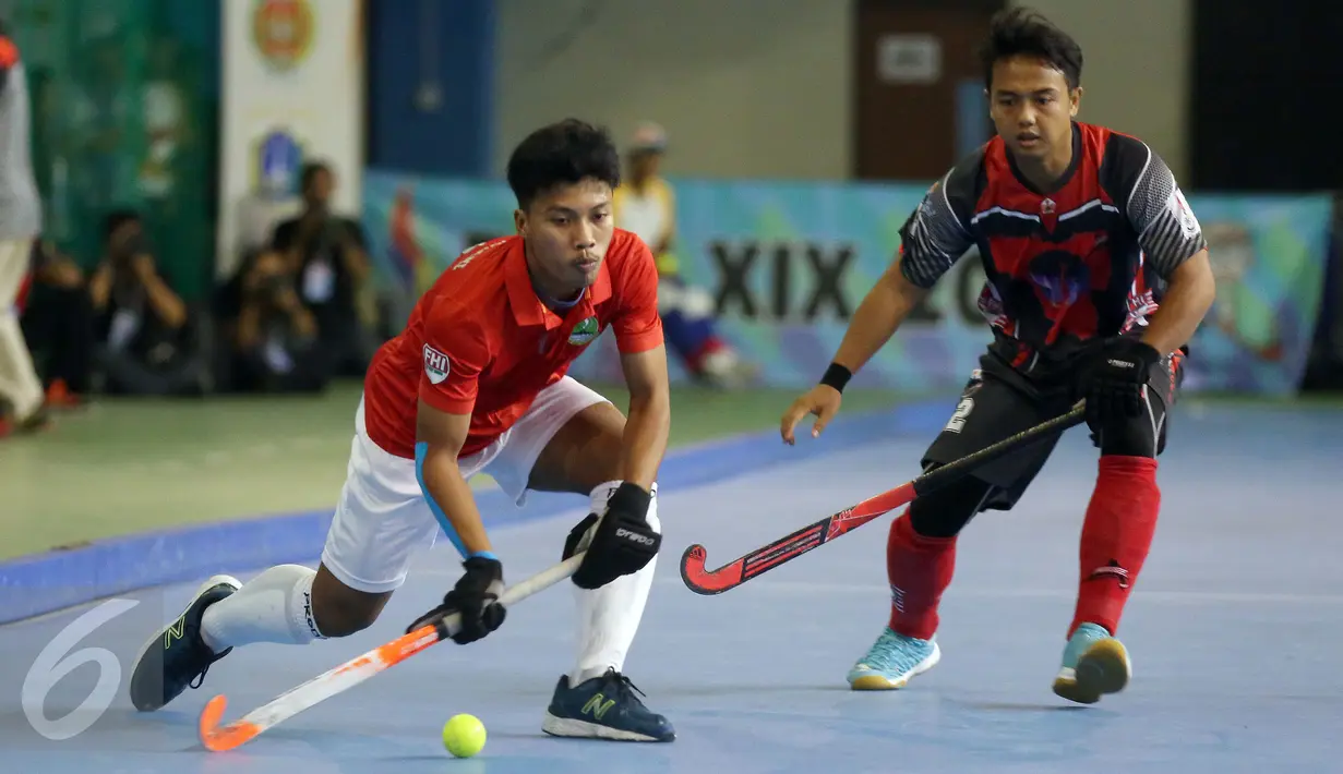 Pemain hoki Jawa Barat, Zein Hamdani (kiri) melewati pemain Jawa Barat saat laga final hoki putra PON XIX Jabar di Gymnasium UPI, Bandung, Senin (19/9). Jawa Barat menundukkan DKI Jakarta dengan skor 3-1. (Liputan6.com/Helmi Fithriansyah)